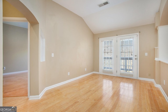 empty room with vaulted ceiling and light wood-type flooring