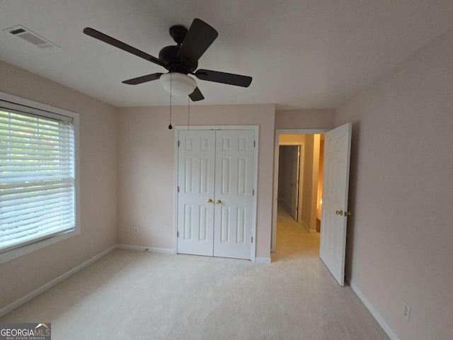 unfurnished bedroom with multiple windows, ceiling fan, light colored carpet, and a closet