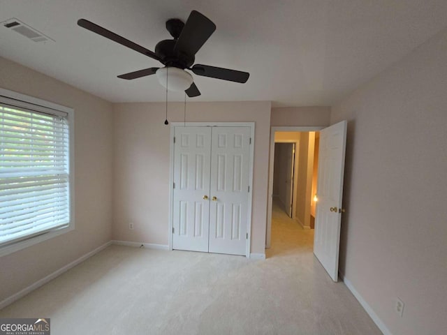 unfurnished bedroom with multiple windows, ceiling fan, light colored carpet, and a closet