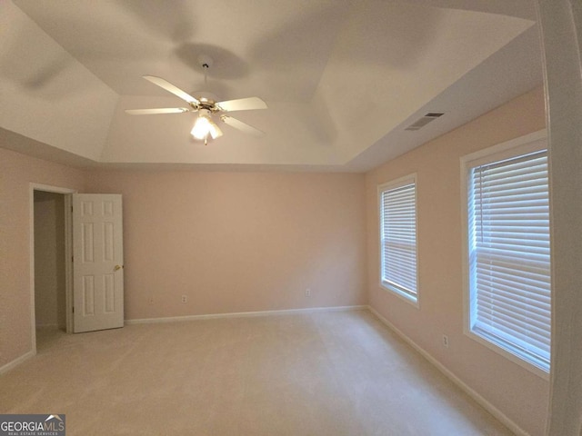 carpeted empty room featuring ceiling fan and a raised ceiling