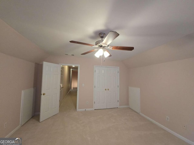 unfurnished bedroom with light carpet, lofted ceiling, a closet, and ceiling fan