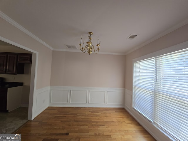 unfurnished dining area featuring ornamental molding, a chandelier, and light hardwood / wood-style flooring