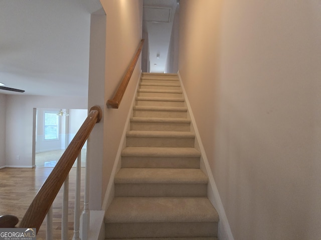 stairway with wood-type flooring and ceiling fan