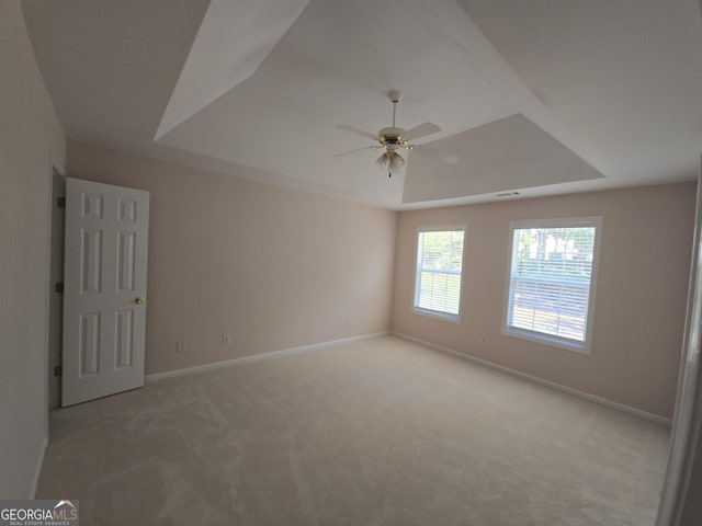 unfurnished room with light colored carpet, a raised ceiling, and ceiling fan