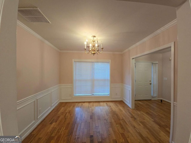 unfurnished dining area featuring hardwood / wood-style flooring, crown molding, and a chandelier