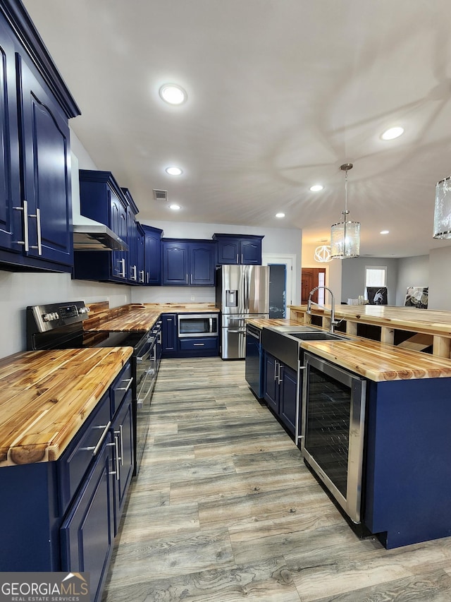 kitchen featuring wine cooler, wood counters, blue cabinets, decorative light fixtures, and black appliances