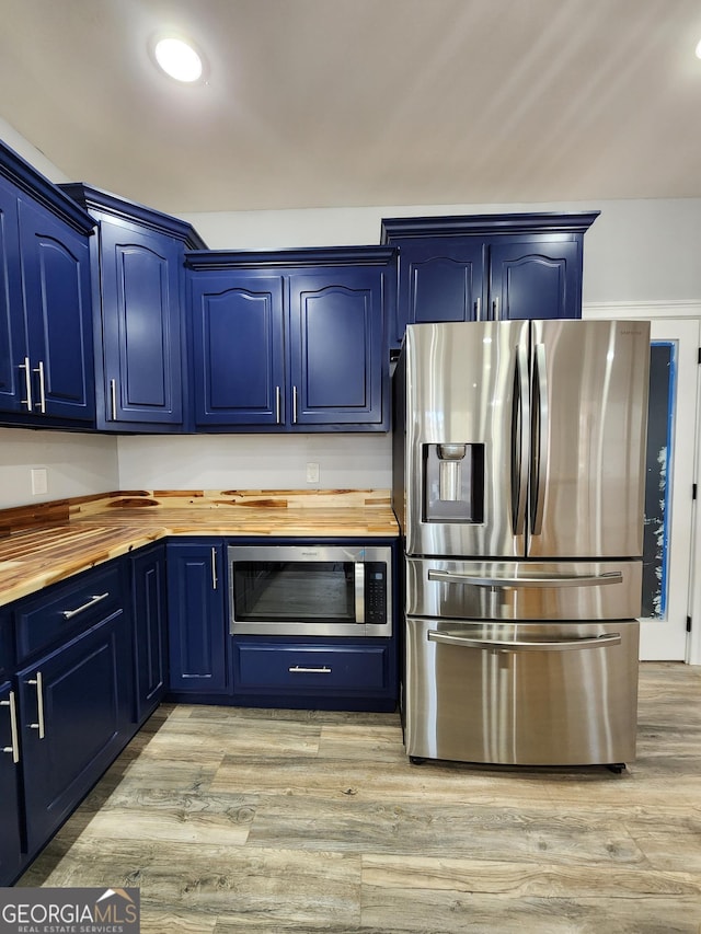 kitchen featuring blue cabinets, appliances with stainless steel finishes, butcher block counters, and light hardwood / wood-style flooring