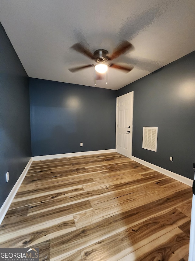 unfurnished room with a textured ceiling, wood-type flooring, and ceiling fan