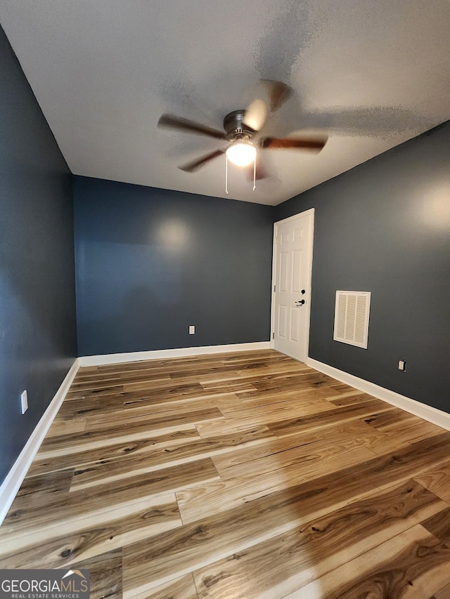 empty room featuring ceiling fan, hardwood / wood-style floors, and a textured ceiling