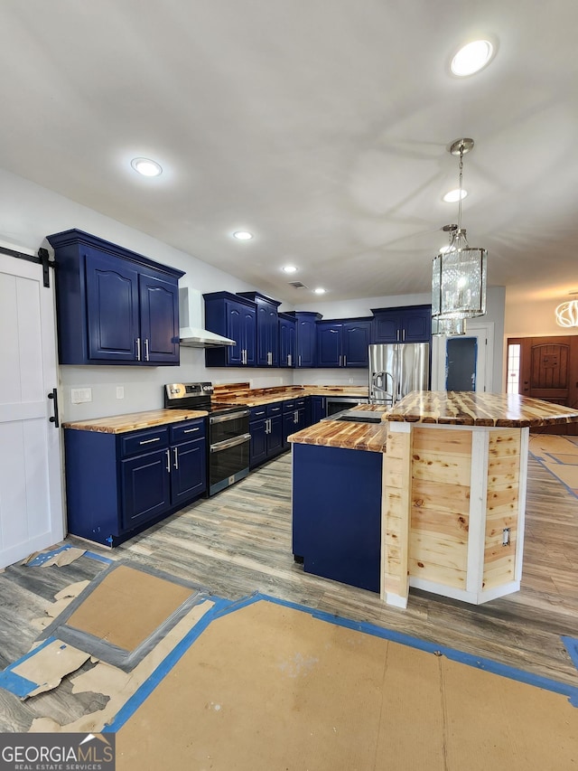 kitchen with blue cabinetry, wooden counters, appliances with stainless steel finishes, hardwood / wood-style floors, and a barn door