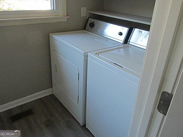 clothes washing area with dark wood-type flooring and washing machine and clothes dryer