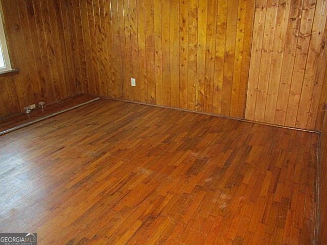 spare room featuring wooden walls and hardwood / wood-style floors