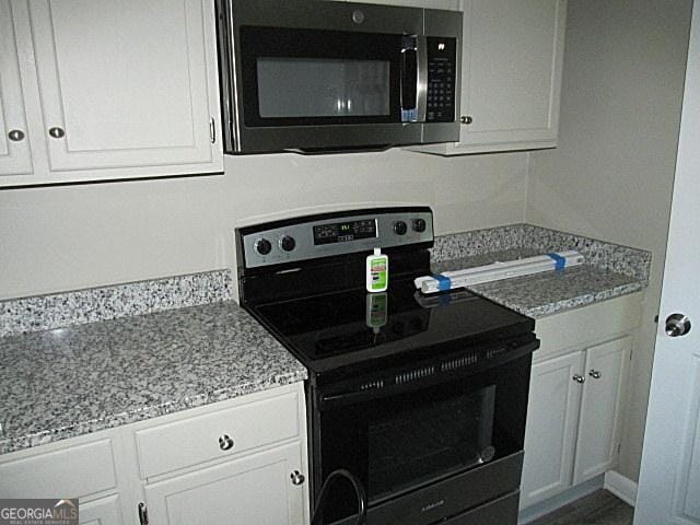 kitchen featuring white cabinetry, light stone counters, and electric stove