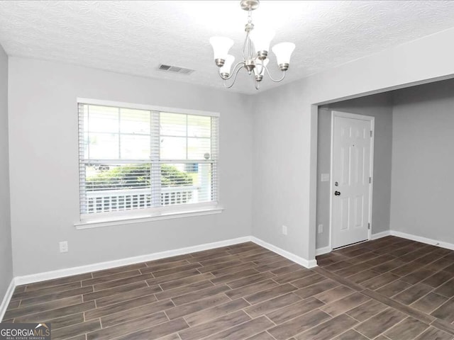 unfurnished room featuring a chandelier and a textured ceiling