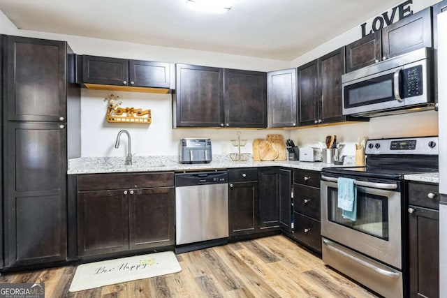 kitchen featuring dark brown cabinetry, appliances with stainless steel finishes, sink, and light wood-type flooring