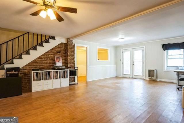 unfurnished living room featuring heating unit, hardwood / wood-style floors, french doors, and ceiling fan