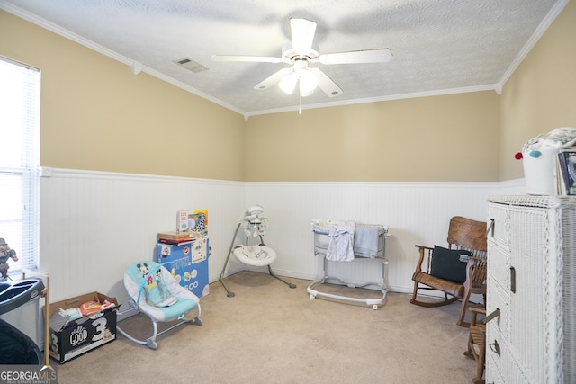 playroom with light carpet, ceiling fan, crown molding, and a textured ceiling