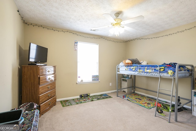 carpeted bedroom with ceiling fan and a textured ceiling