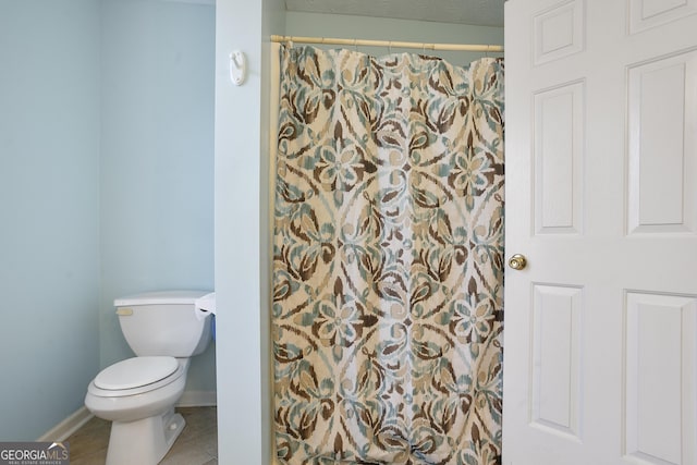 bathroom featuring curtained shower, tile patterned floors, and toilet