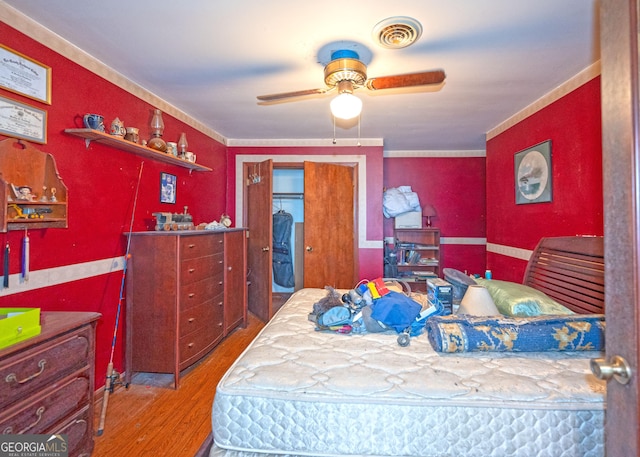 bedroom with hardwood / wood-style flooring, ornamental molding, and ceiling fan