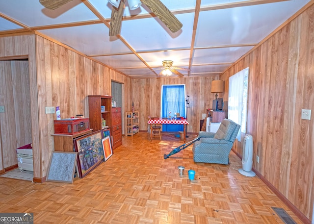 sitting room featuring light parquet floors, wooden walls, and ceiling fan