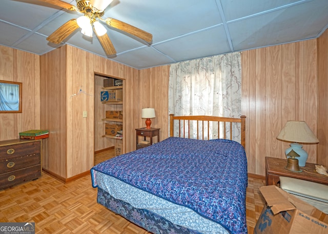 bedroom featuring ceiling fan, parquet flooring, and wood walls