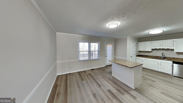 kitchen with dishwasher, sink, white cabinets, a center island, and a textured ceiling