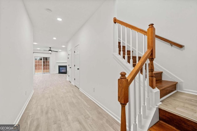 stairs with wood-type flooring and ceiling fan