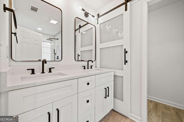 bathroom with vanity, wood-type flooring, and tiled shower