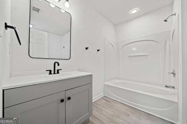 bathroom featuring hardwood / wood-style flooring, vanity, a textured ceiling, and  shower combination