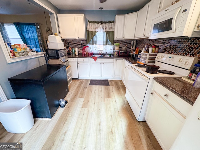 kitchen featuring white cabinetry, hanging light fixtures, white appliances, and sink