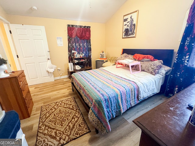 bedroom with vaulted ceiling and light wood-type flooring