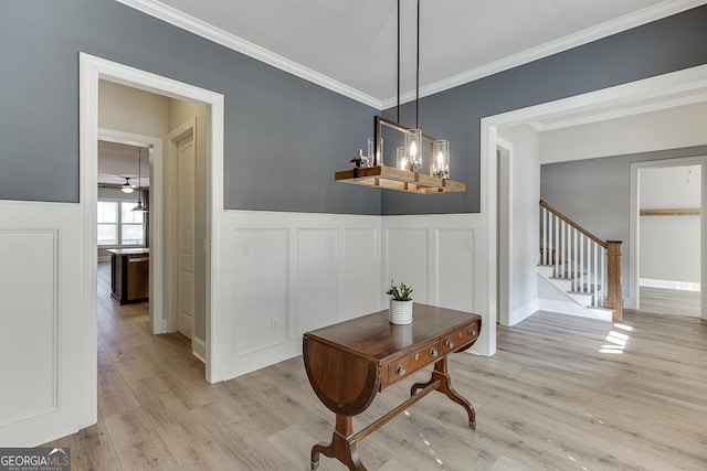 interior space with light wood-type flooring, a wainscoted wall, stairway, and crown molding