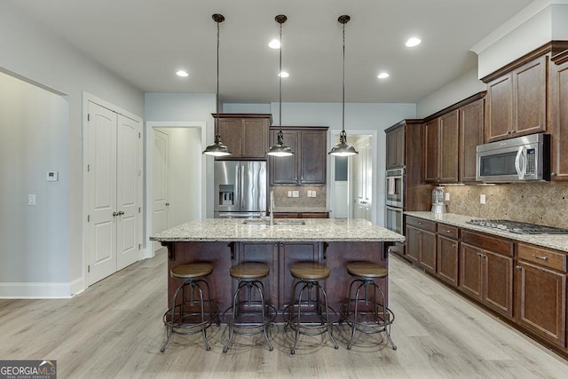 kitchen with an island with sink, stainless steel appliances, a sink, and a kitchen breakfast bar