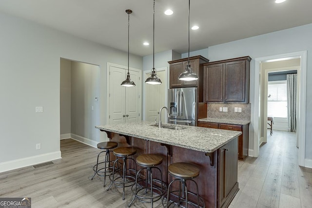 kitchen with a sink, tasteful backsplash, stainless steel fridge, and light wood-style floors