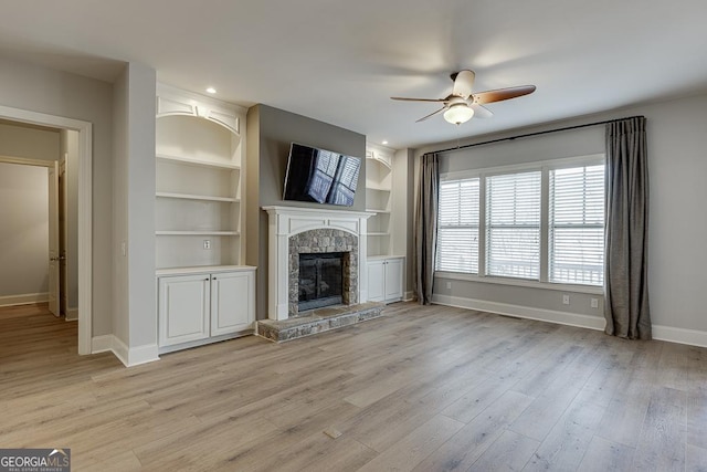 unfurnished living room with light wood-style floors, a fireplace, baseboards, and built in features