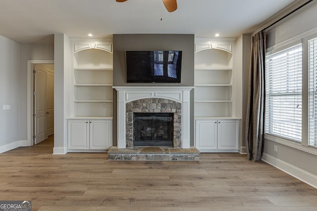 unfurnished living room featuring light wood-style floors, baseboards, and a stone fireplace