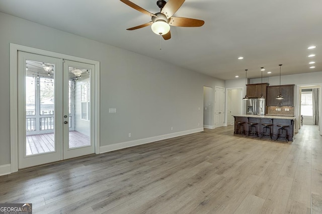 unfurnished living room featuring baseboards, ceiling fan, french doors, light wood-style floors, and recessed lighting