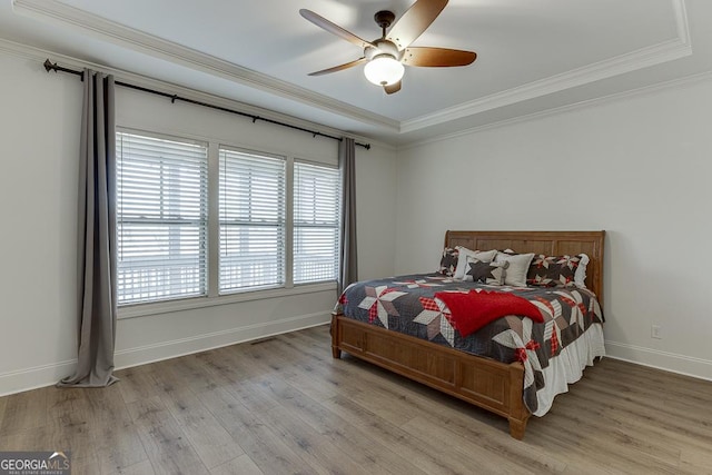 bedroom with ornamental molding, light wood-type flooring, a ceiling fan, and baseboards