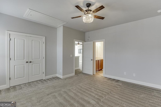 unfurnished bedroom featuring ensuite bathroom, light carpet, baseboards, a closet, and attic access