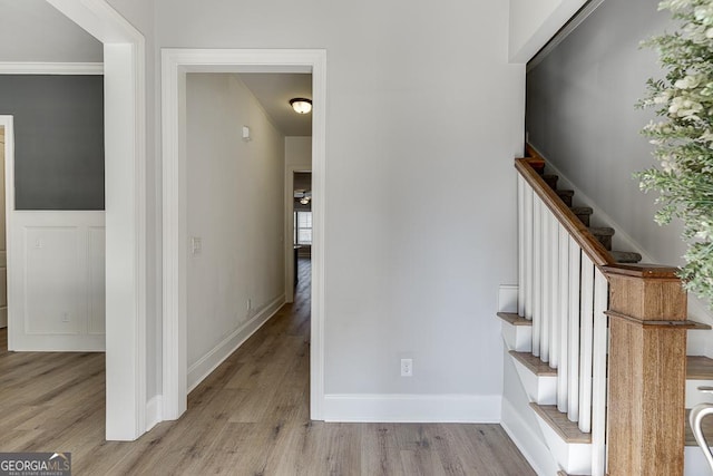 staircase with a wainscoted wall and wood finished floors