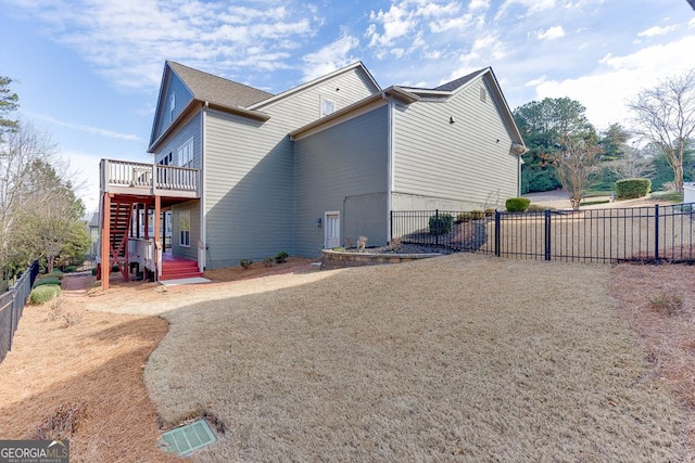 view of side of property with stairway, fence, and a deck