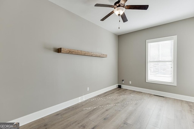 unfurnished room featuring a ceiling fan, visible vents, baseboards, and wood finished floors