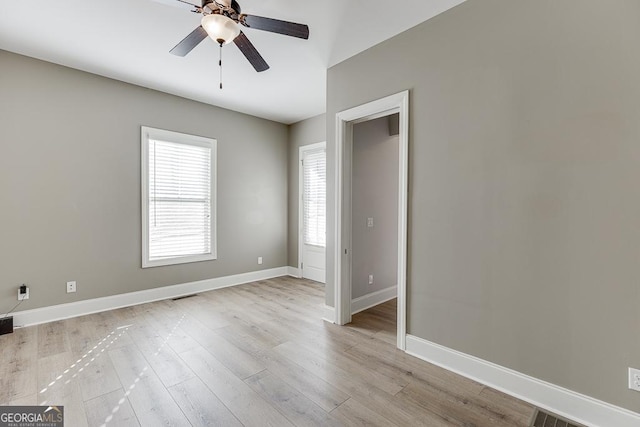 unfurnished room featuring light wood finished floors, visible vents, baseboards, and a ceiling fan