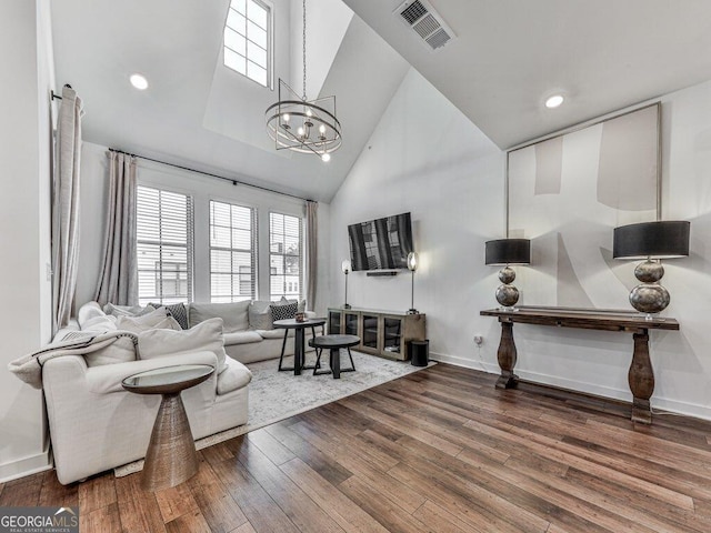 living room with a chandelier, high vaulted ceiling, and hardwood / wood-style floors