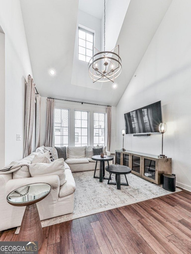 living room featuring hardwood / wood-style flooring, a chandelier, and a high ceiling