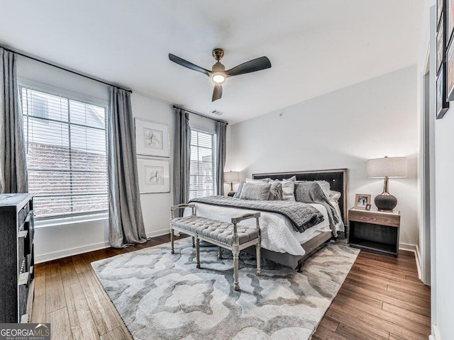 bedroom featuring ceiling fan, dark hardwood / wood-style flooring, and multiple windows