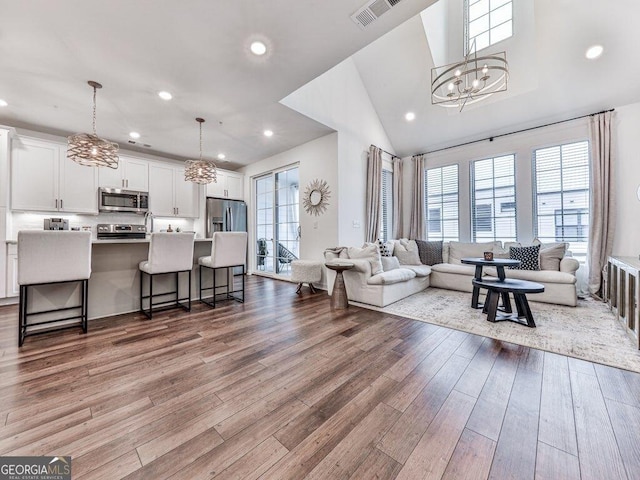 living room featuring lofted ceiling, a notable chandelier, and light hardwood / wood-style floors