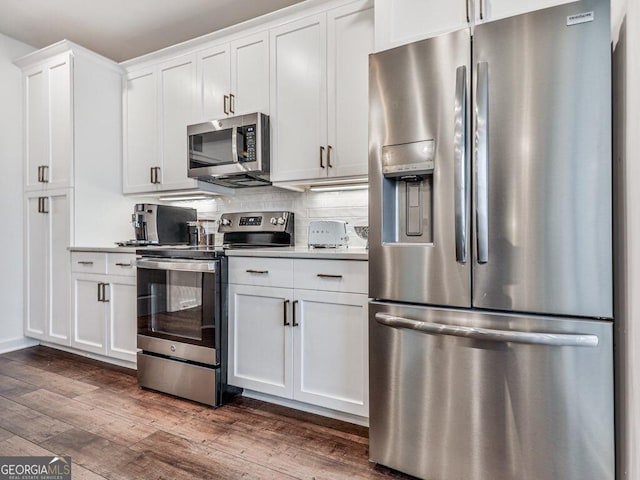 kitchen featuring dark hardwood / wood-style flooring, tasteful backsplash, white cabinets, and appliances with stainless steel finishes