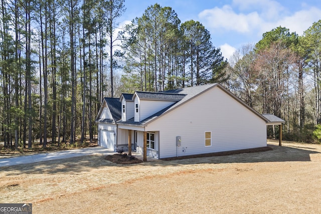 view of home's exterior with a garage, driveway, and a shingled roof